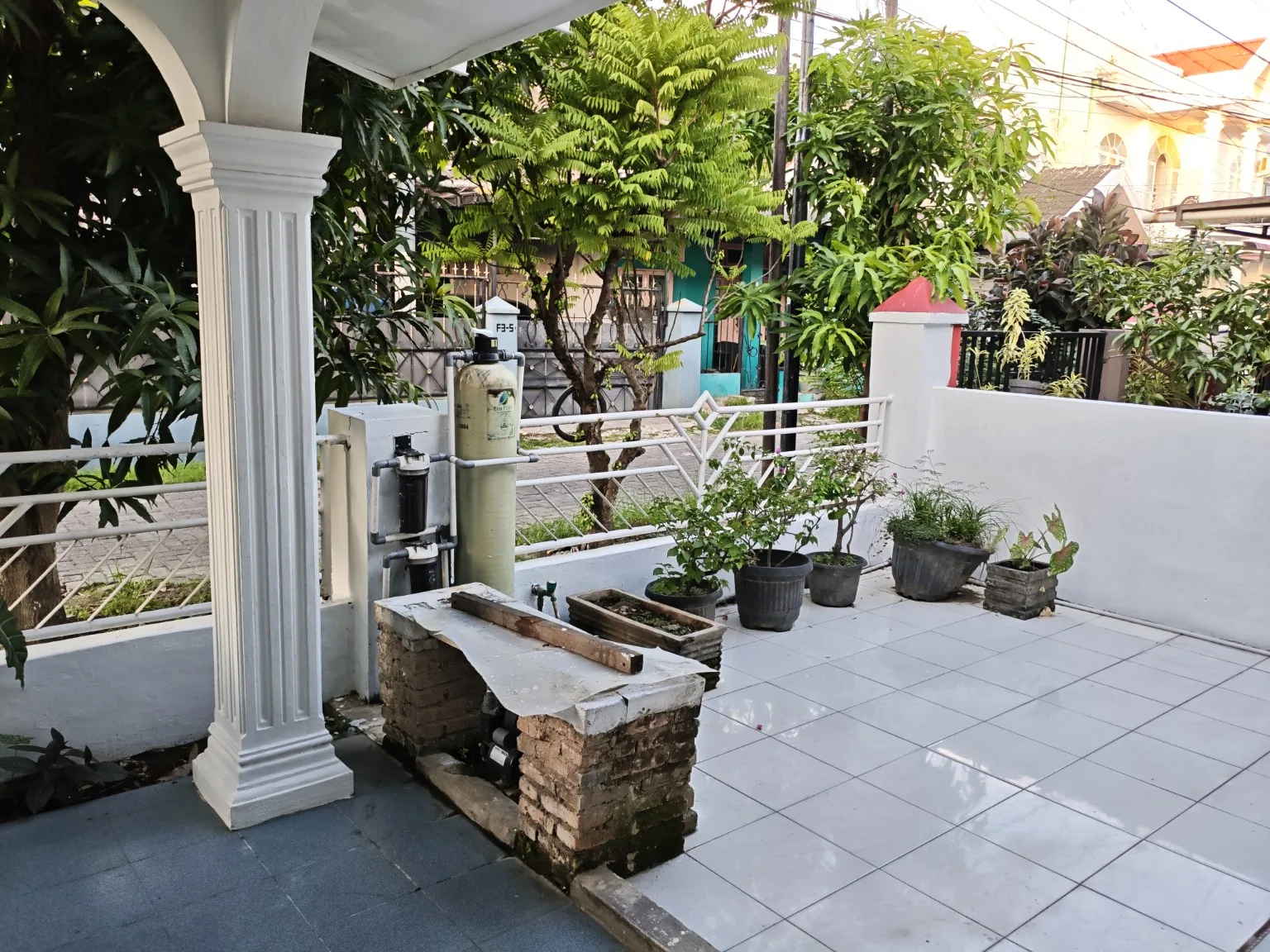 Halaman depan rumah dengan tanaman dan perangkat filter air